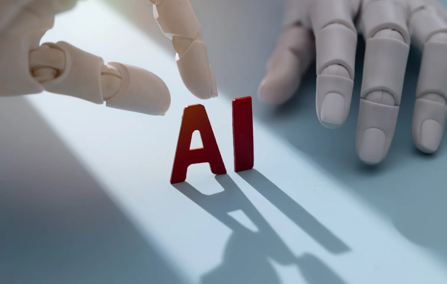 Robotic hands assembling the letters 'AI,' representing unmonitored AI deployment across the enterprise.